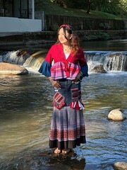 Portrait of a young traveler wearing ethnic hill tribe clothing by a river in Northern Thailand.