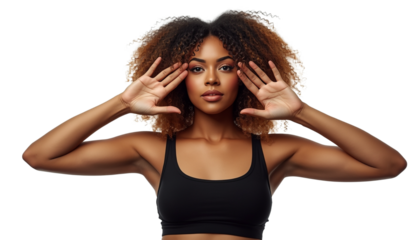 A young woman in a black sports bra framing her face with her hands for the concept of fitness and wellness.