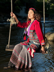 Serene Woman in Traditional Ethnic Attire Relaxing on a Wooden Swing Over a River
