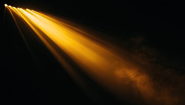 Dramatic golden beam of light radiating through atmospheric haze against a stark black background