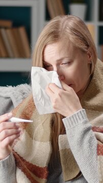 A woman deals with cold and flu symptoms at home during rain.