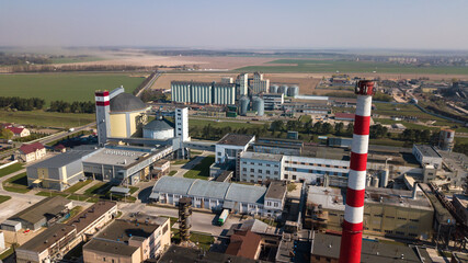 A huge oil refinery with metal structures, pipes and distillation of the complex with burning lights at dusk. Aerial view