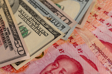 red Chinese cash in denominations of one hundred yuan and dollars , a pile of paper cash of American and Chinese money , Chinese banknotes of 100 yuan