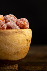 small orange fruits of fragrant kumquat dried in syrup , round dehydrated kumquat fruit in a wooden bowl