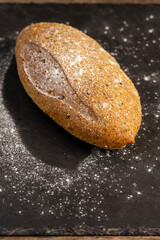 a fresh soft loaf of bread on black slate, a freshly baked loaf of rye bread lies on the table