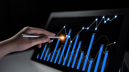 A business professional uses a stylus to analyze financial data on a tablet, showcasing growth charts and trends in a modern workspace environment. Scalp