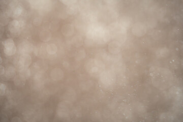 White particles or snowflakes falling diagonally on a light soft background with a motion blur effect.