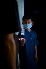 A image depicting a young child in a face mask being handed a small packet of white powder by an out-of-focus adult, highlighting themes of exploitation, substance misuse, and danger in darkness.