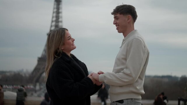 A romantic couple holds hands in Paris France with the Eiffel Tower visible in the background The young lovers are enjoying their time in Europe showcasing travel love and romance in a handheld shot.