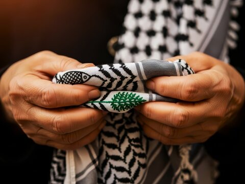 A person holding a keffiyeh scarf in their hands closely