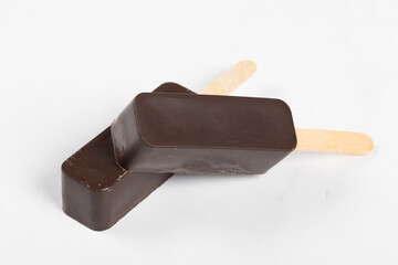 Dark Chocolate cake is rectangular in shape. On a wooden stick. White background. Close-up