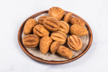 Holiday cookies in the shape of nuts, cones, mushrooms and shells. Stuffed with boiled condensed milk. On a plate. White background. Merry Christmas. New Year	