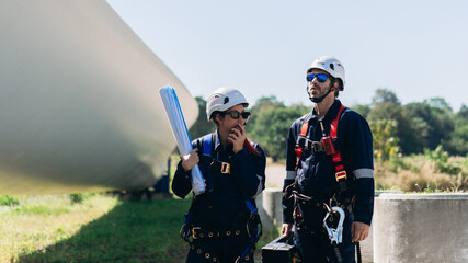 Professional wind turbine engineers preparing and inspecting equipment for installation and maintenance at a renewable energy site, teamwork, clean power, and sustainable technology.