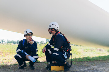 Professional wind turbine engineers preparing and inspecting equipment for installation and maintenance at a renewable energy site, teamwork, clean power, and sustainable technology.