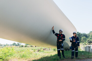 Professional wind turbine engineers preparing and inspecting equipment for installation and maintenance at a renewable energy site, teamwork, clean power, and sustainable technology.