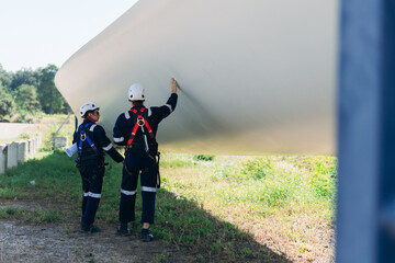 Professional wind turbine engineers preparing and inspecting equipment for installation and maintenance at a renewable energy site, teamwork, clean power, and sustainable technology.