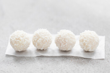 Coconut candy ball with whole almonds inside. On paper. On a light background. Close-up