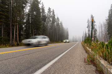 Obraz premium Cars rush by on a road in the Wyoming Wilderness