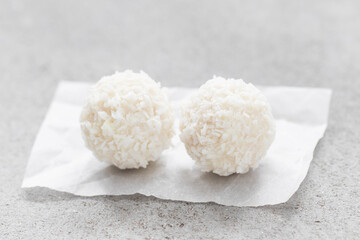 Two Vegan Coconut candy balls. On paper. Light background. Close-up