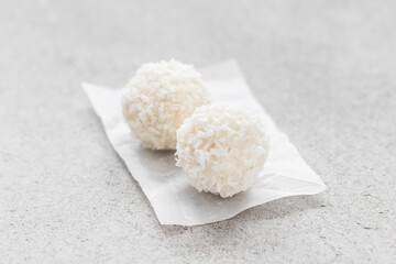 Two Dessert Coconut candy balls. On paper. Light background. Close-up