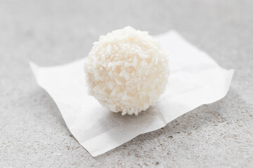 Coconut candy ball. On paper. A light background. Close-up