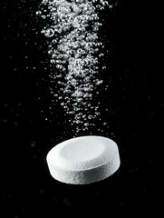 Antacid tablet dropping into water dissolves and fizzes releasing gas bubbles fast