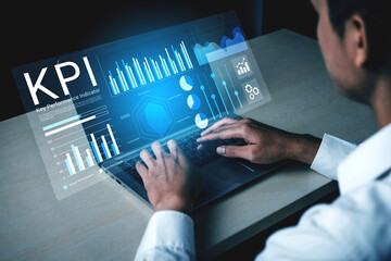 A business professional engages in analysis of key performance indicators using a laptop. Futuristic graphics and data visualizations enhance the modern office experience. Gantry