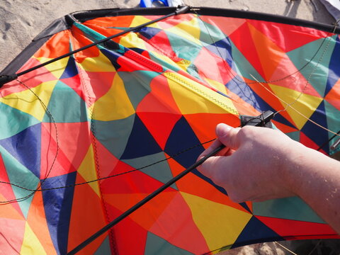 Person assembling a multi-colored kite on a sunny spring day at Nida Beach, Neringa, Curonian Spit, Lithuania