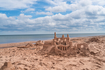 A sand castle on the beach with the ocean in the background.