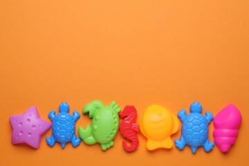 Fototapeta premium Children's beach toys on orange background, flat lay. Space for text