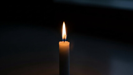 Fototapeta premium Single white candle glowing softly in darkness, solemn remembrance atmosphere.