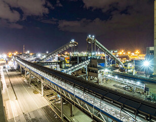 Obraz premium Vibrant nighttime industrial scene featuring conveyor belts processing scrap metal at a recycling plant. Ideal for projects on sustainability, engineering, and efficient resource recovery.
