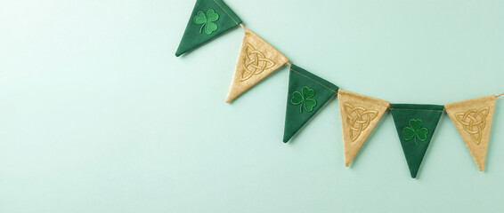Bunting garland arranging green shamrock and gold celtic knot flags on studio background for st. Patrick's day celebration