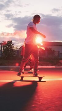 Group of young people skateboarding on the road in the early morningwith red sugnal flare, slow motion
