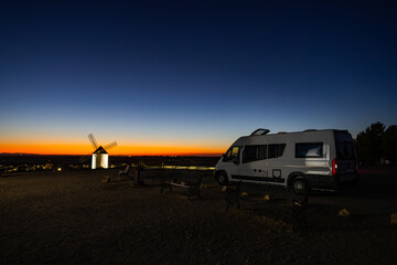 Camper van travelling at sunset near Mota del Cuervo windmill