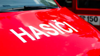 Detail of the inscription HASICI on the hood of the red fire truck of the Czech fire department (ENG = Firemen), Czech fire department phone number 150 on another fire truck in the background