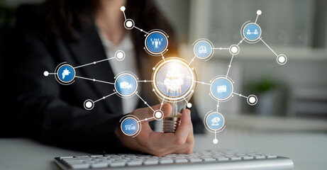 A businesswoman holds a light bulb symbolizing ideas and innovation, surrounded by digital icons in a contemporary office, showcasing technology and connection. Crux