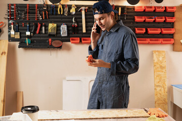 craftsman wood master talking on mobile phone with client in workshop carpenter