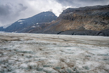 View into the Athabasca Glacier in Jasper National Park with cloudy sky with shoal visible. 