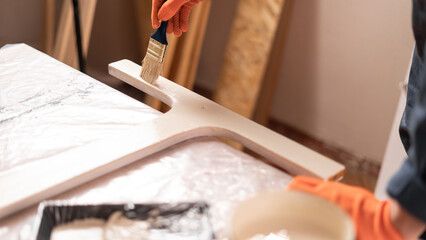 Close-Up of carpenter painting wooden table working In Workshop