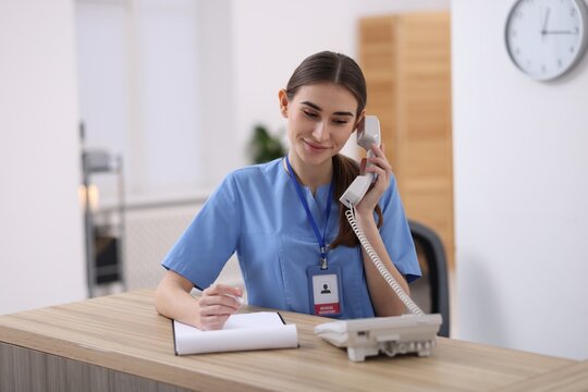 Medical assistant answering phone at reception in clinic