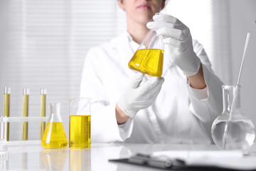 Scientist checking motor oil quality at table in laboratory, closeup. Space for text