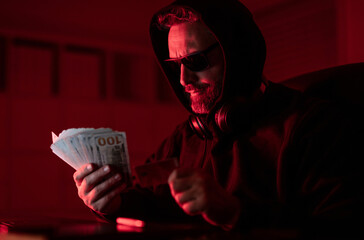 Hacker programmer in hoodie at office laptop, neon. Hacker attack. Hacker at night in office count...