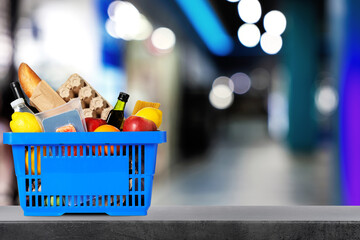 Shopping basket full of products on table in supermarket. Space for text