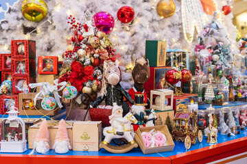 Moscow, Russia,A vibrant Christmas market stall displaying various holiday decorations, including stuffed animals, snow globes, and rocking horses, against a backdrop of a white Christmas tree.