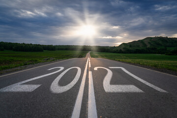 New Year 2027. The numbers &lsquo;2027&rsquo; written on a paved road illuminated by rays of sunlight breaking through a cloudy sky. Concept of planning, opportunities, hope, and life changes.