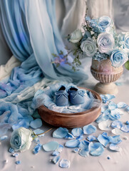 Still Life with Blue Baby Shoes, Roses, and Draped Fabric on Table &ndash; Baby Boy Backdrop with Copy Space