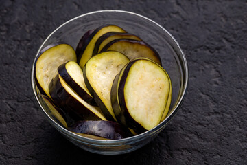 Fresh Sliced Eggplant in Glass Bowl on Wooden and Dark Background