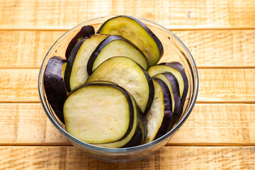 Fresh Sliced Eggplant in Glass Bowl on Wooden and Dark Background