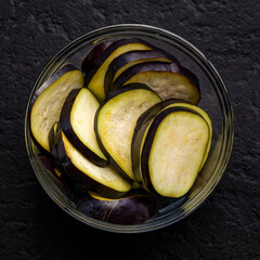 Fresh Sliced Eggplant in Glass Bowl on Wooden and Dark Background